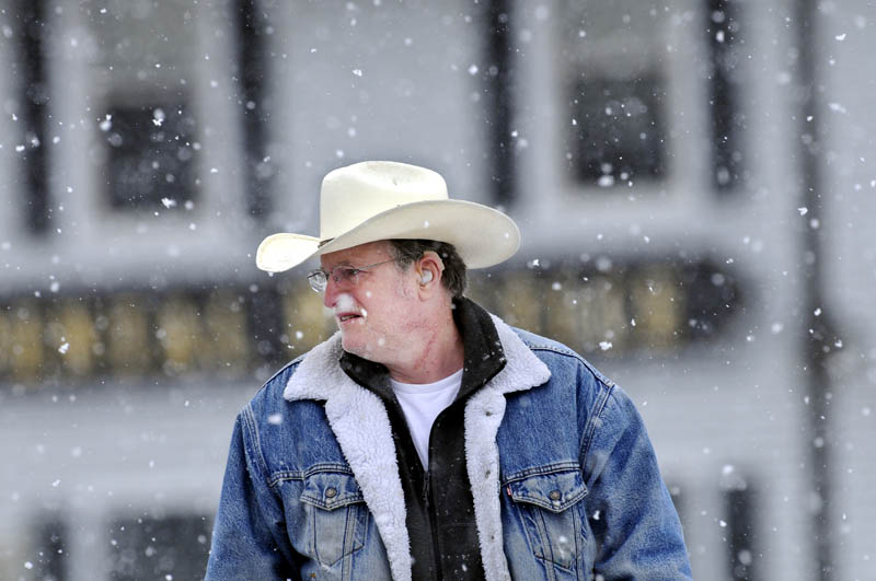 Lewis Armstrong, of Augusta, walks through Memorial Circle in Augusta on Monday during a snow shower.