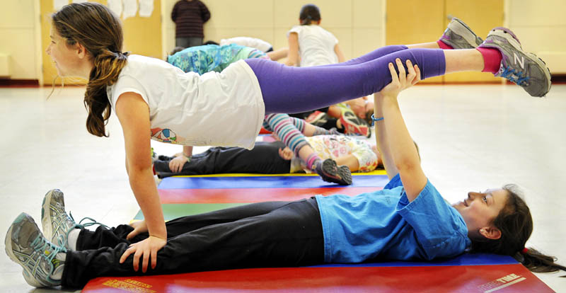 Kate Mohlar, 9, holds up her classmate, Ella Schmidt, 9, during circus training Thursday for students at the Readfield Elementary School. Students learned about juggling, tight rope walking and acrobatics from Rick Davis, a performer from the Vermont based Circus Smirkus, before a circus show to be held at the school on Friday at 7 p.m.