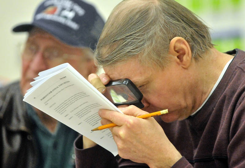 Deane Mason takes a close look at the articles up for vote during the annual Town Meeting at the Albion Elementary School Saturday.