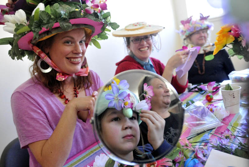 Bria Sanborn, left, Liz Bailey, back center and Beatrice Borden, far right, laugh as Brian Evans, 8, of South Solon, makes the final adjustments to his Easter bonnett in the mirror at the Waterville Easter Bonnett Contest at the Waterville Public Library on Saturday.