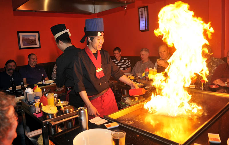 Chef Ricky Huang, right, fires up the hibachi as he prepares dinner for a group of diners at Mirakuya Mirakuya Steak House, at 150 Kennedy Memorial Drive in the JFK Plaza in Waterville, Wednesday night.