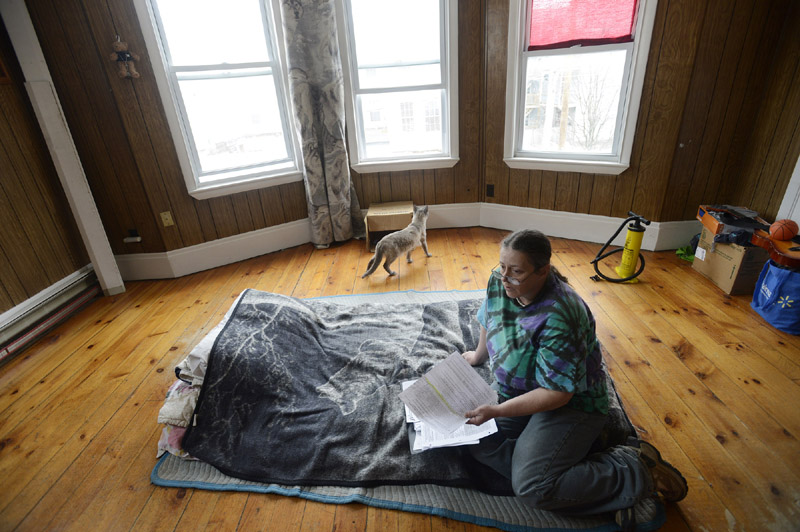 Katrina LaCourse 47, of Lewiston, looks over paperwork in her apartment Wednesday. LaCourse was recently removed removed from the city's General Assistance welfare rolls.
