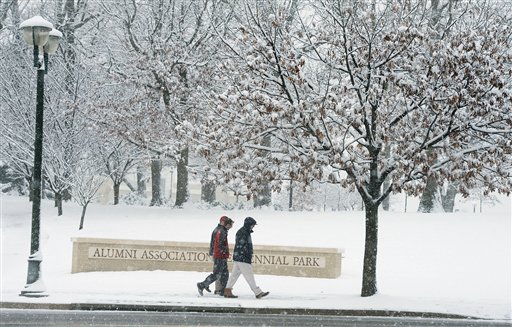 James Madison University students walk across a snow-covered campus in Harrisonburg, Va., Sunday evening. A meteorologist with the National Weather Service in Sterling, Va., said more than 3 inches of snow had been reported by 8 a.m. Monday at Washington Dulles International Airport, and more than an inch at Reagan National Airport.