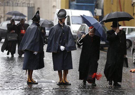 Cardinal Carlo Caffarra, second from right, and Cardinal Raymond Leo Burke, right, walk past two Swiss guards as they leave after a meeting at the Vatican on Friday.