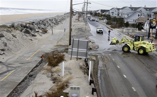 Crews clear a flooded road Thursday in Sea Bright, N.J., after an overnight storm caused the ocean to breach a temporary dune. The lingering late-winter storm brought new damage Thursday to parts of the Jersey shore still struggling to recover from Superstorm Sandy.