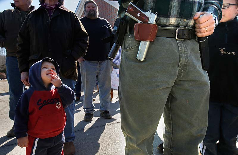 Samson Hiltz, 2, looks up to his father, Jeremy Hiltz of Chelsea, pastor at the Windsor Memorial Baptist Church, while the two attend a rally protesting gun control legislation and supporting gun rights in Wiscasset on Saturday.