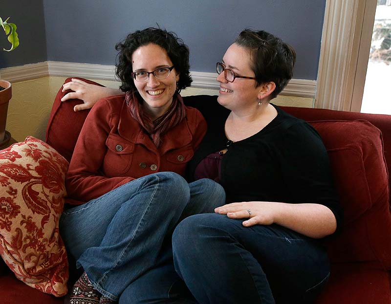 Amanda Hollander, left, and Katy McCormack sit together at their home in Portland last week. The women are getting married over Memorial Day weekend. They wanted to wait so they could invite friends and relatives and make all the arrangements that come with a wedding in which 224 people are being invited.