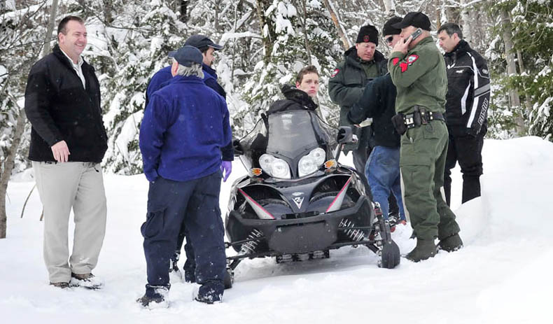 Seventeen-year-old Nicholas Joy is surrounded by game wardens and others that brought him out of the woods Tuesday. Joy spent two night lost in the woods near Sugarloaf ski area. At right is Joseph Paul, who picked up Joy on the snowmobile and at left is Carrabassett Valley police chief Mark Lopez.