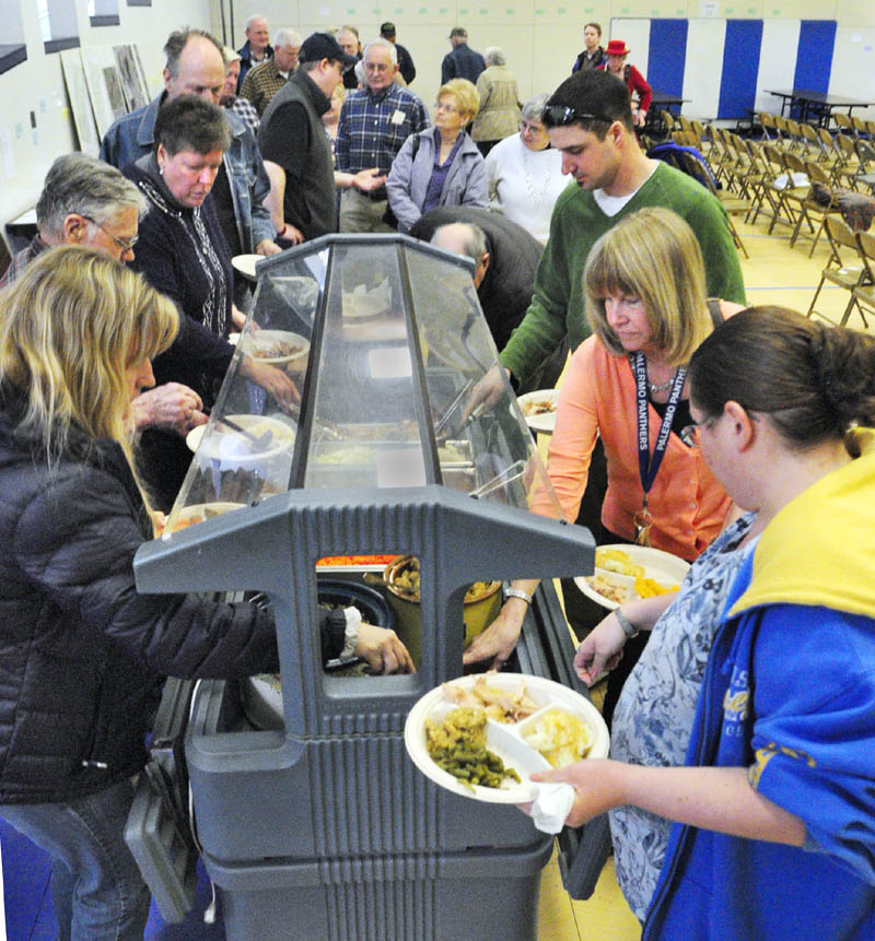 People serve themselves a turkey dinner during a lunch break in the annual town meeting on Saturday at the Palermo Consolidated School. The lunch was prepared by members of the Branch Mills Grange.