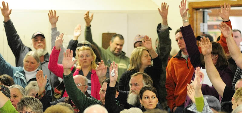 Residents raise their hands to vote during the Pittston town meeting on Saturday in the Pittston Elementary School gym.