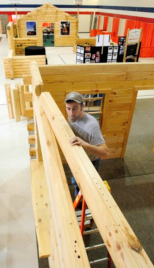 Matt Rutchick puts the top layer on a display model that he and other workers from Coventry Log Homes, based in Woodsville, NH, put together on Thursday inside the Augusta Armory. The 11th Annual Maine Log Home, Timber Frame, & Restoration Show will be held there this weekend. Show hours are Friday noon to 7p.m., Saturday, 10 a.m. to 7 p.m., and Sunday 10 a.m. to 4 p.m.