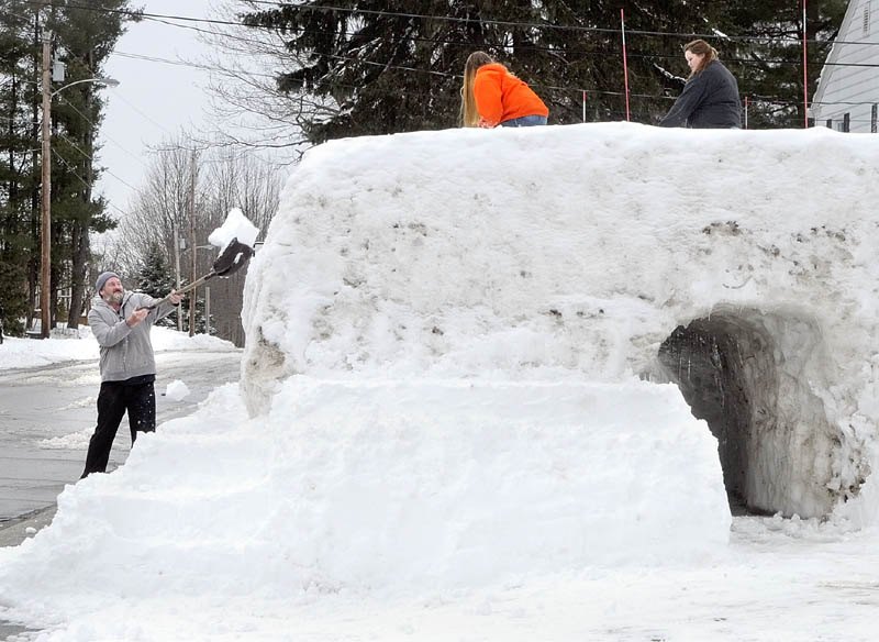 Steven St. Pierre tosses shovelful of snow on Wednesday up onto a snow fort he and his daughters Shania St. Pierre, center, and Natasha St. Pierre, built on Sixth Avenue in Augusta.
