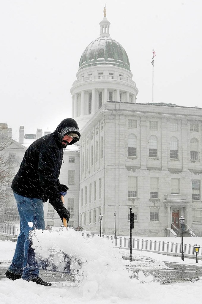 Jason Sirios shovels snow at the State House complex on Tuesday in Augusta. He was part of the Bureau of General Services crew clearing sidewalks and lots.