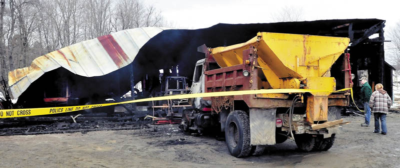 Arthur Kennedy and his friend, Ceri Zeolla, on Sunday look over the burned remains of the Bingham town garage and equipment that was destroyed by fire late Saturday evening. Kennedy said he plows for the town and two of his own plow trucks and a loader were damaged. Kennedy said he believes the fire was intentionally set.