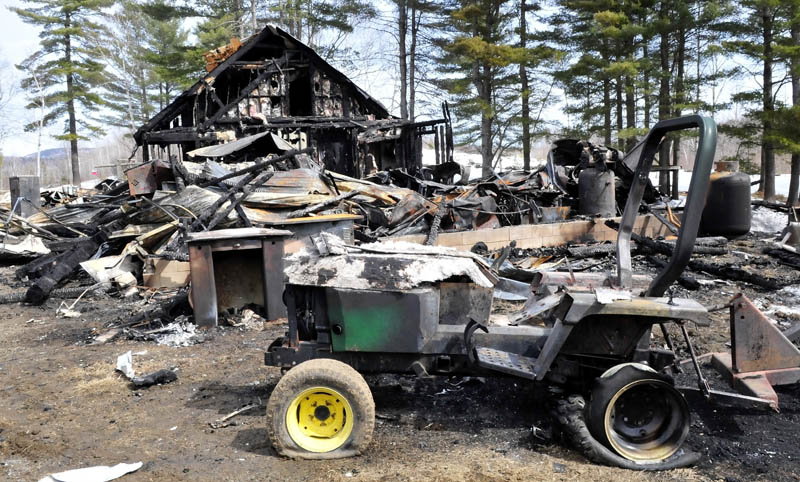 The remains of a home, garage and equipment at the property of Tellis Fenwick in Freeman Township, which were destroyed in a Saturday fire, as seen on Sunday, The home was located off the Freeman Ridge Road near the Kingfield and New Portland town lines.