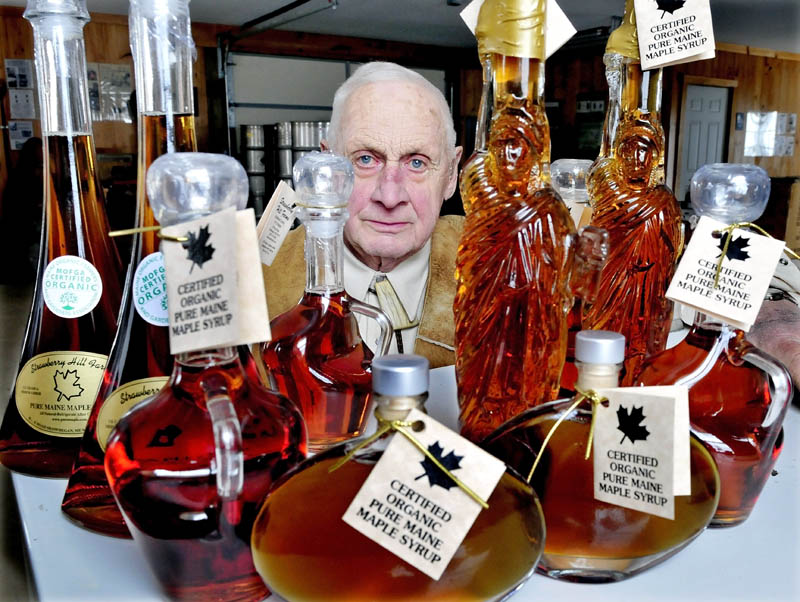 Jack Steeves with some of the various glass containers filled with maple syrup made at Strawberry Hill Farms in Skowhegan.