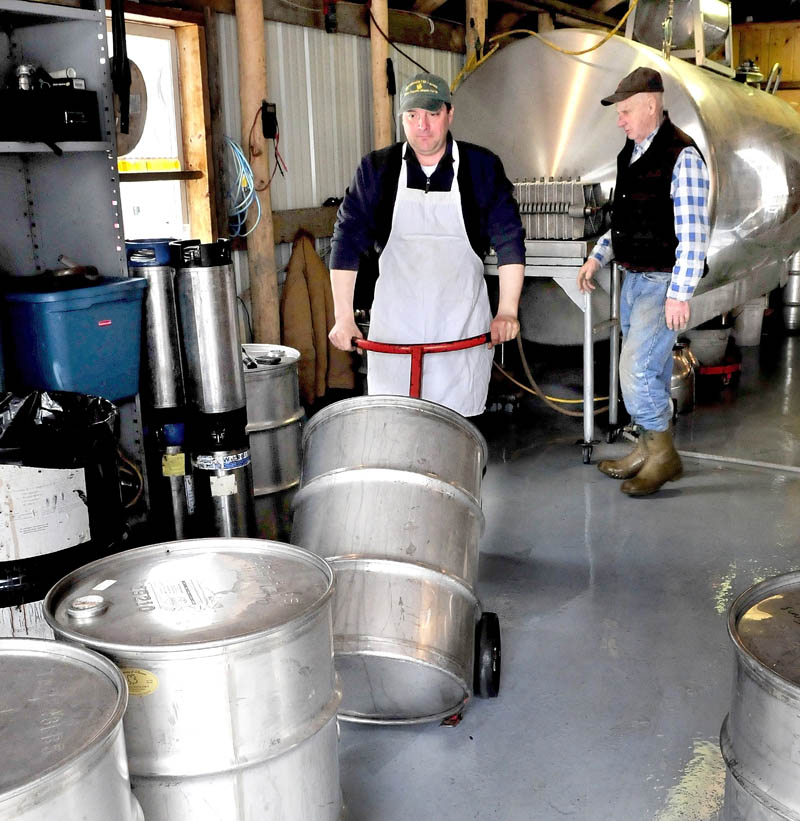 Jeremy Steeves moves a barrel filled with 40 gallons of hot maple syrup as his father, Jack, prepares to fill another barrel inside the sugar camp building at Strawberry Hill Farm in Skowhegan on March 11.