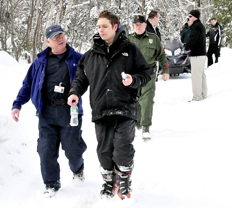 Missing skier Nicholas Joy is escorted to an ambulance by Peter Boucher of Northstar Ambulance when he emerged from the woods last Tuesday. Snowmobiler Joseph Paul, far right, found him walking on a trail near Sugarloaf Mountain.