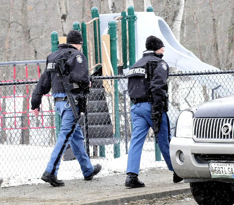 Maine State Police troopers walk past a playground during a lockdown at the Mill Stream Elementary School in Norridgewock, while searching for a reported man with a rifle, on Monday.