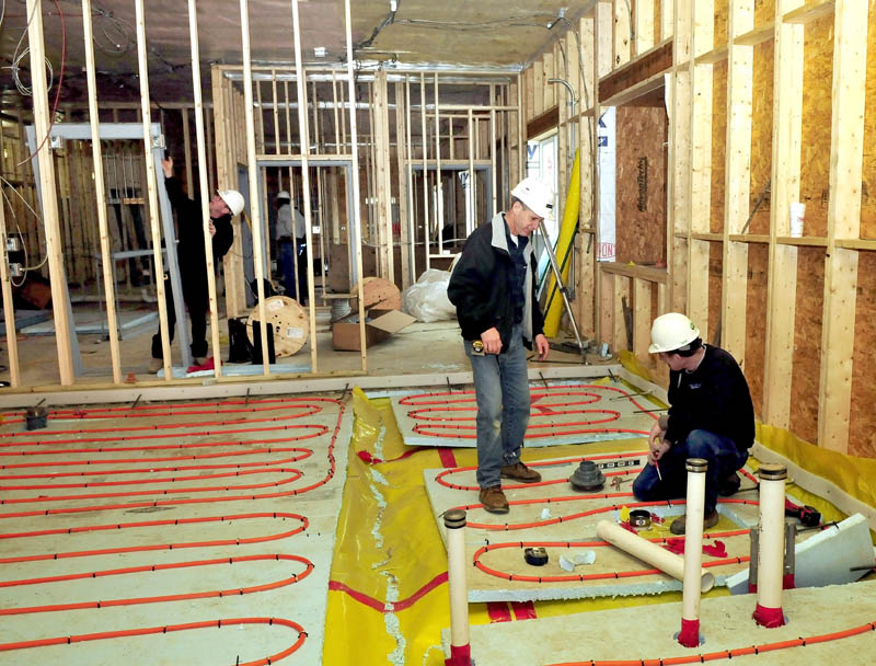 Wright-Ryan company Superintendent Millard Nadeau, standing, speaks with Dave Poulin, as he installs radiant heat material in the floor of a prisoner cell inside the new Waterville police building on Tuesday. Nadeau said the project is on schedule and slated to be finished this June.