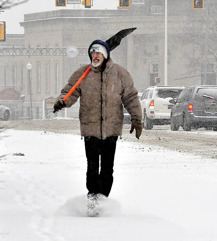 OPPORTUNITY KNOCKS: Ralph Norton gets at least one more day of winter to make money shoveling sidewalks and porches as he and his snow shovel trudge along Main Street in Waterville on a snowy Tuesday. Wednesday is the first day of spring, but forecasts are calling for more snow this week.