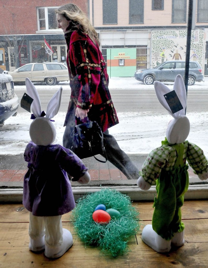 A late-winter snow storm greeted Maine on Tuesday and even these Easter bunnies were caught staring out the Variety Drug store window in Skowhegan, as Cynthia Cushing walks into the wind and snow blowing outside,