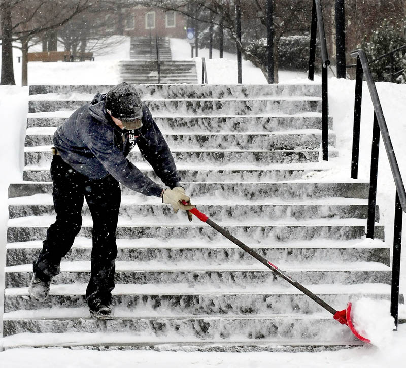 Colby College employee Nicholas Giroux finishes clearing snow from the seemingly endless set of stairs on campus in Waterville during the snow storm on Tuesday.