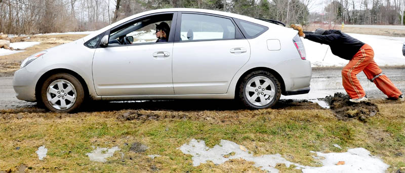 As the temperature rises and rain falls, the frost is leaving the ground and producing perfect conditions to get stuck in the mud. Phil Crandlemire pushes as Arunee Rodsatra, of Thailand, and now a Sidney resident, on Tuesday attempt to free her car from a muddy rut in Waterville. After getting her car free Rodsatra said,"I've never experienced driving in mud before."