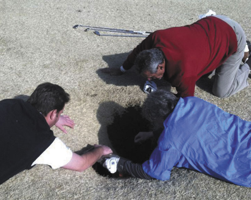 SINKHOLE: In this cell phone image taken Friday and provided by golfmanna.com, Hank Martinez, top, Ed Magaletta, right, and Russ Nobbe, look into an 18-foot-deep and 10-foot- wide sinkhole that golfer Mark Minhal fell into while playing golf at the Annbriar Golf Course in Waterloo, Ill. Mihal, 43, a mortgage broker from Creve Coeur, Mo., was hoisted to safety with a rope and suffered a dislocated shoulder.