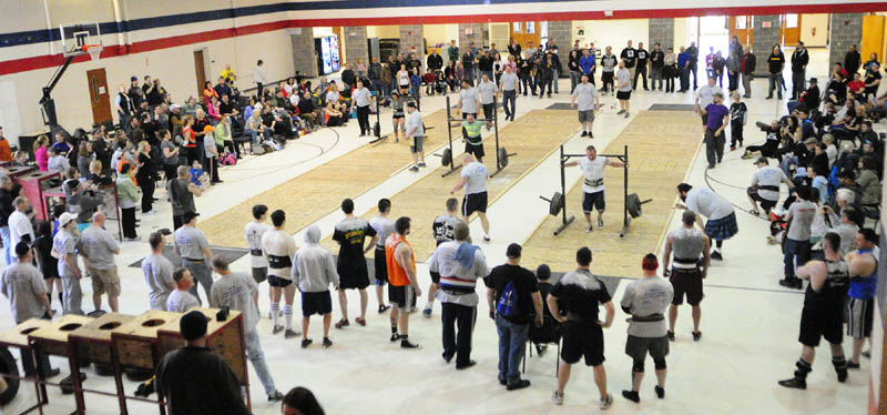 Three lanes of competitors walk carrying heavy loads, in the yoke walk event during the 2013 Central Maine Strongman contest on Saturday at the Augusta armory.
