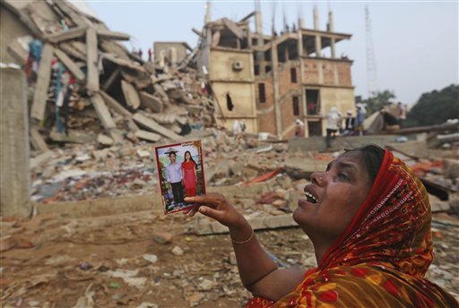 A Bangladeshi woman weeps as she holds a picture of herself and her missing husband while she waits near the site of the building collapse.