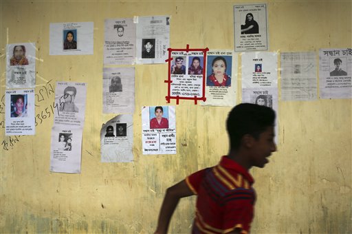 A boy runs past a school turned makeshift morgue with portraits of missing garment factory workers plastered over its walls on Monday.
