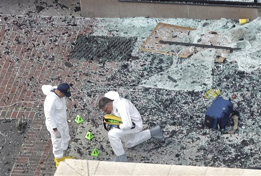 Two men in hazardous materials suits put numbers on the shattered glass and debris as they investigate the scene at the first bombing on Boylston Street near the finish line of the 2013 Boston Marathon, a day after two blasts killed three and injured over 170 people.