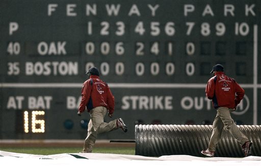 The grounds crew moves to cover the field after the seven inning of a baseball game between the Oakland Athletics and the Boston Red Sox at Fenway Park in Boston, Tuesday, April 23, 2013. (AP Photo/Winslow Townson)