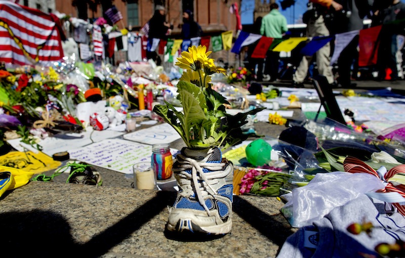 A memento of flowers in a running shoe rests at a makeshift memorial in Boston's Back Bay neighborhood on Thursday, April 18, 2013, a few blocks from the finish line of the Boston Marathon, where people continue to bring special objects to mourn and honor those who were killed and injured after two bombs exploded at the finish line of the race. (AP Photo/Craig Ruttle)