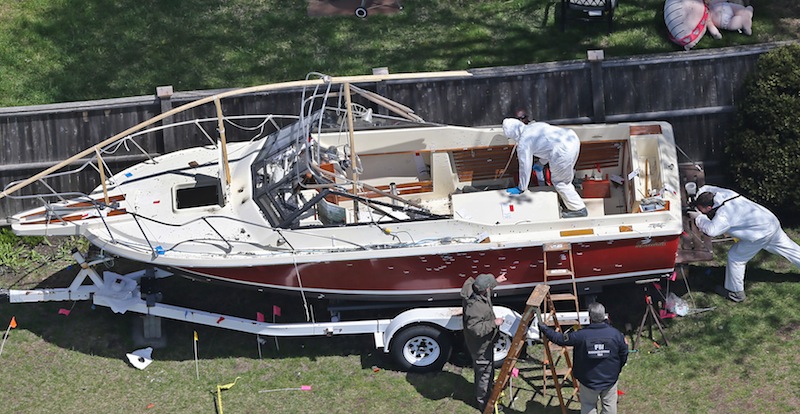The boat where the bombing suspect was found is inspected by the FBI in a yard on Franklin Street in Watertown. It shows spattered blood on the wheel fenders of a boat trailer along with bullet holes.