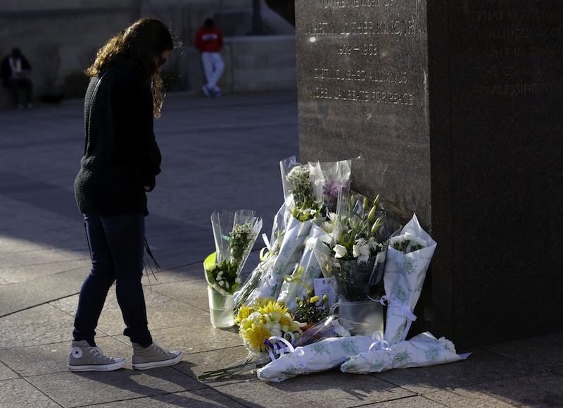 A woman reflects in front of a makeshift memorial honoring Boston University student Lingzi Lu, who was killed in the Boston Marathon explosions, Wednesday, April 17, 2013, in Boston. The city continues to cope following Monday's explosions near the finish line of the marathon, which claimed three lives. (AP Photo/Julio Cortez)