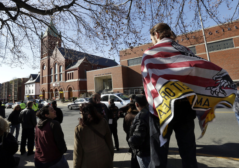 Devon Morancie of Littleton, Mass., wears a flag on his back as a crowd gathers outside the funeral for Boston Marathon bomb victim Krystle Campbell, 29, at St. Joseph's Church in Medford, Mass., on Monday.