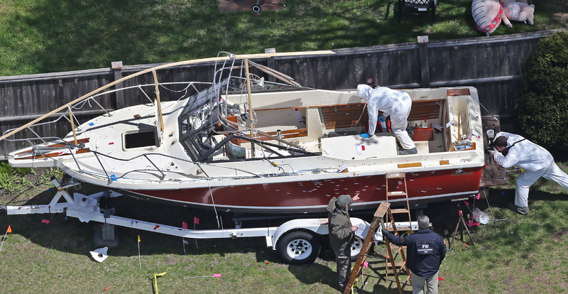 Investigators from the FBI inspect the boat where Boston Marathon bombing suspect Dzhokhar Tsarnaev was found hiding Friday night in a backyard in Watertown, Mass. Bullet holes are visible in the hull.