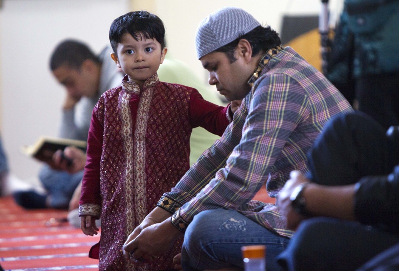 A boy stands next to his father during a prayer service at the Islamic Society of Boston mosque in Cambridge, Mass., on Friday.