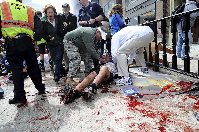 In this April 15, 2013 photo, an injured person is helped on the sidewalk near the Boston Marathon finish line following an explosion in Boston. The bombs that made Boston look like a combat zone have also brought battlefield medicine to their civilian victims. A decade of wars in Iraq and Afghanistan has sharpened skills and scalpels, leading to dramatic advances that are now being used to treat the 13 amputees and nearly a dozen other patients still fighting to keep damaged limbs. (AP Photo/MetroWest Daily News, Ken McGagh, File)