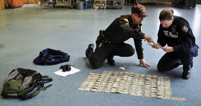 Somerset County Sheriff's Department Cpl. Gene Cole, left, helps Maine State Police Trooper Diane Perkins-Vance inventory money recovered from Christopher Knight on Tuesday at the Pine Tree Camp in Rome. Knight, a hermit who lived in the woods since April 1986, was apprehended when he broke into the camp, police claim. He was captured carrying a knapsack and bag of tools. Many of bills date from the 1980s and 1990s, Perkins-Vance said, and were never circulated by Knight.