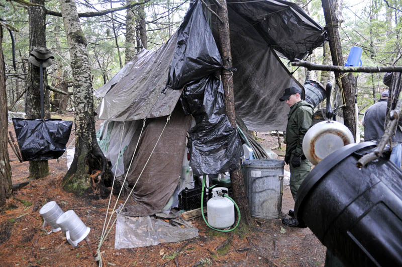 Staff photo by Andy Molloy District Game Warden Aaron Cross inspects Christopher Knight's camp Tuesday April 9, 2013 in a remote, wooded section of Rome. Police believe Knight, who went into the woods near Belgrade in 1986, was a hermit who committed hundreds of burglaries to sustain himself.