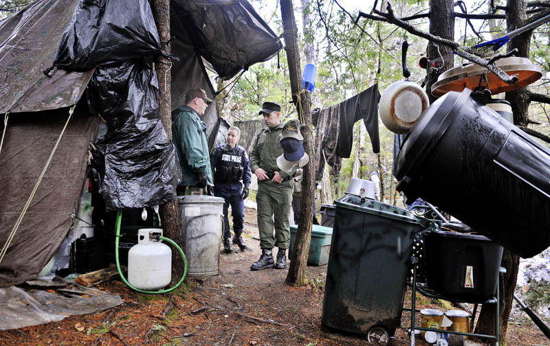 Game Warden Sgt. Terry Hughes, right, Maine State Police Trooper Diane Perkins-Vance, center, and Somerset County Deputy Sheriff Jeremy Leal on Tuesday inspect Christopher Knight's camp in a remote, wooded section of Rome.