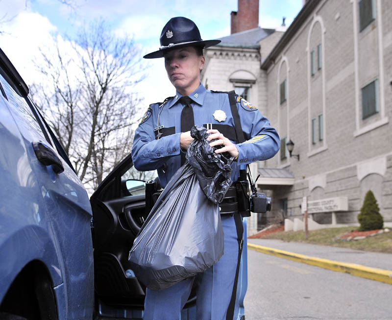 Maine State Police Trooper Diane Perkins-Vance carries a bag of clothing, seized from Christopher Knight, on Sunday at the Kennebec County Correctional Center. Perkins-Vance arrested Knight, who is suspected of committing more than 1,000 burglaries while living in the woods for 27 years, on new charges Sunday, and his bail was increased to $250,000, from $5,000.