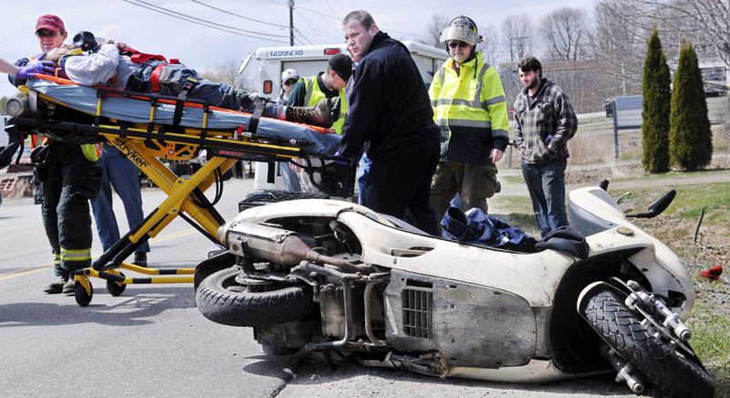 Firefighters carry the victim of a mo-ped accident Tuesday on the Hallowell Road in Chelsea. State police are investigating the wreck, which injured the driver.