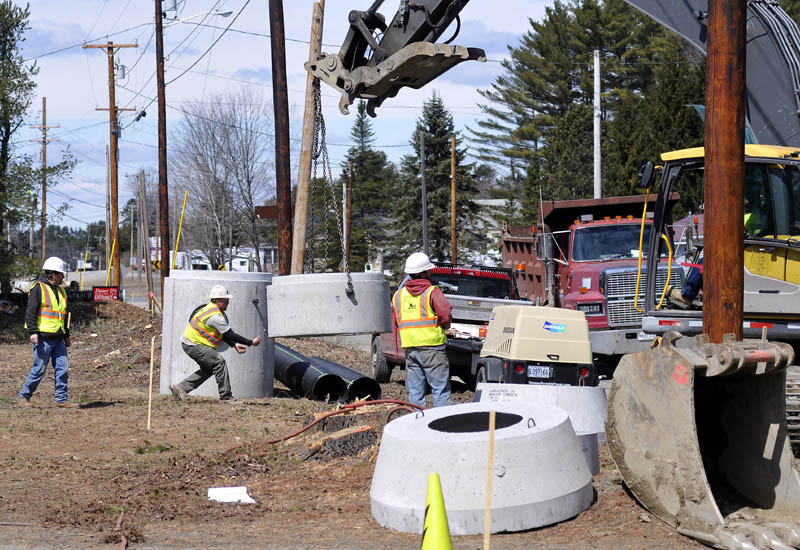 Contractors set up drainage culverts on Old Belgrade Road, near Civic Center Drive in Augusta, on Monday. The work is part of a nearly $13 million project to connect routes 3 and 27 and allow Interstate 95's exit 113 to function in all directions.