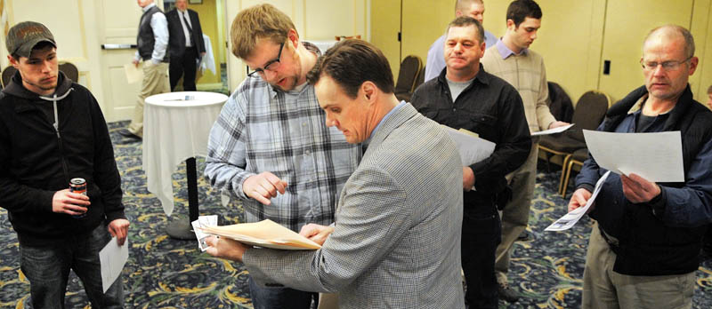 Recruiter David Bartholomew, center, reviews a resume from Knowell Matthews of Fairfield on Wednesday during a job fair for Summit Natural Gas in Augusta. More than 100 people attended the event to learn how to apply for positions with the Colorado firm that plans to install and manage a natural gas pipeline in Kennebec County.