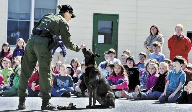 Game Warden Michelle Merrifield and her tracking dog, Duchess, demonstrate how they train together during a visit to the Belgrade Central School on Monday.