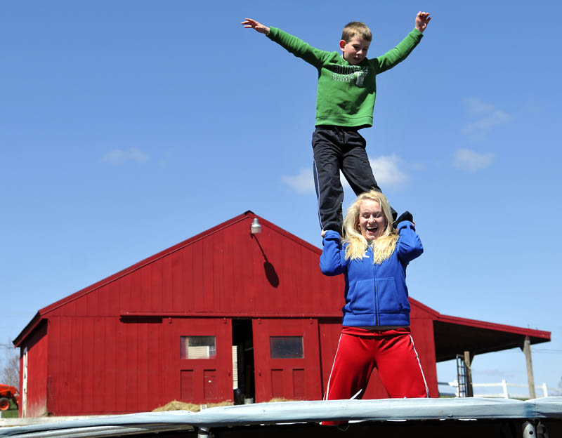 Anna Kulinski, 14, lets go of her brother, Jason, 9, while practicing acrobatics Sunday on the trampoline behind their Monmouth farmhouse. The siblings were practicing flips and landings that the elder Kulinski performs on the Monmouth Academy cheering squad.